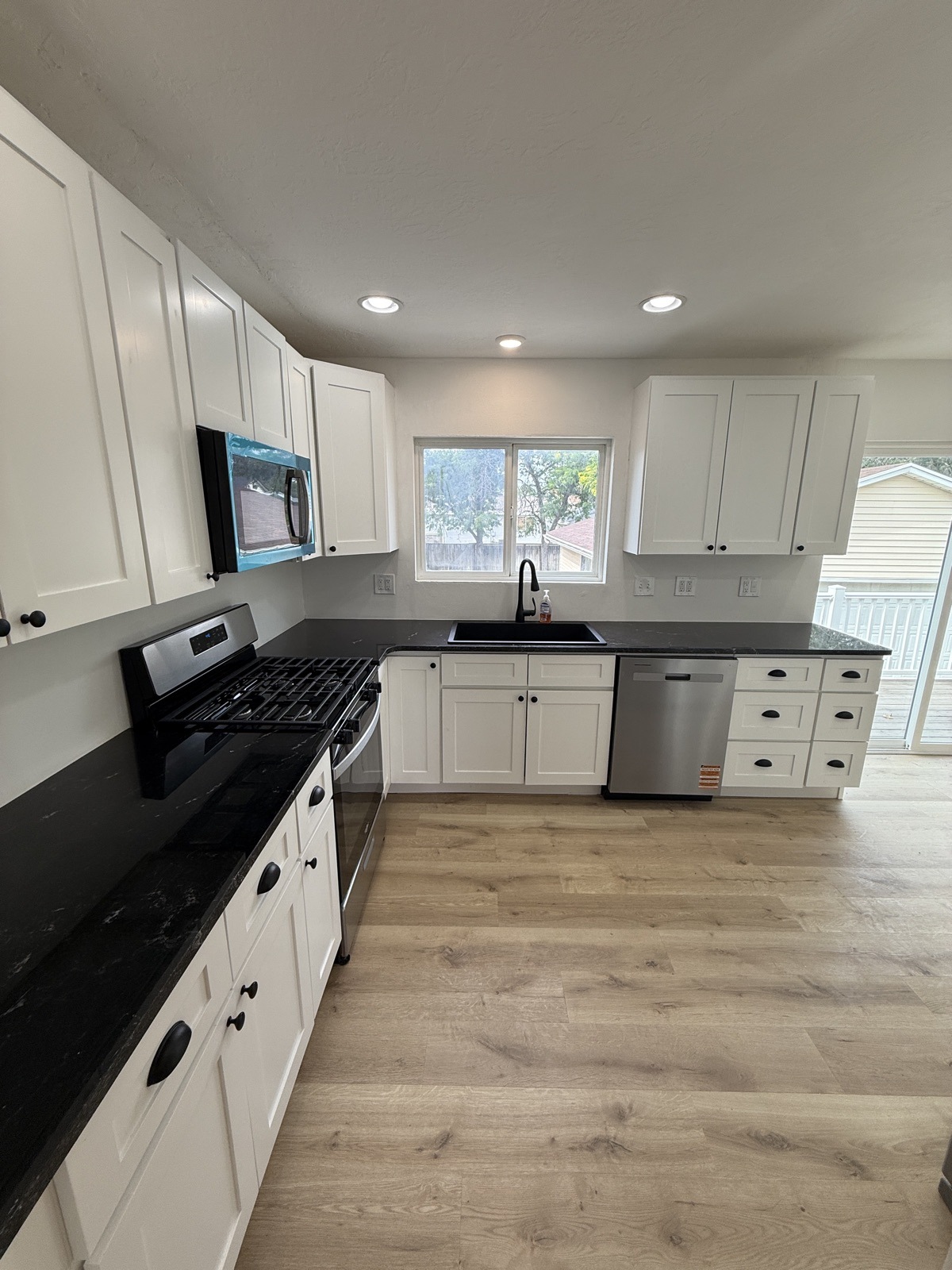 Renovated kitchen with white shaker cabinets, dark counters and stainless appliances