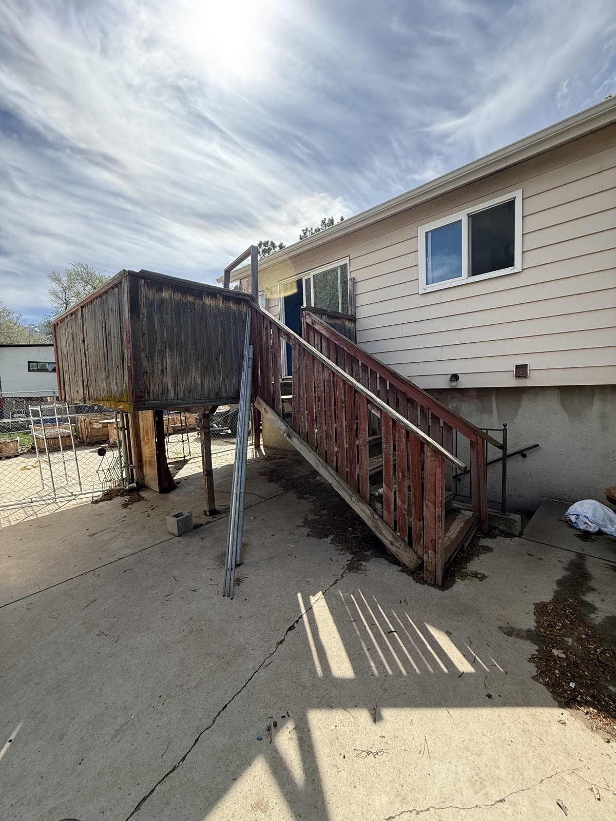 Raised timber deck with rotted boards, a broken railing and a staircase pulling away from the house